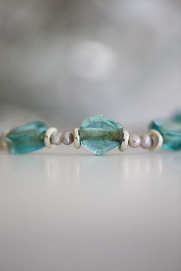 Close-up of a beaded bracelet with turquoise gems on a gray background.
