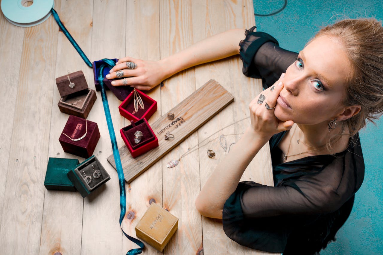 our-services-01 From above serious businesswoman looking up at camera while sitting at wooden table with small jewelry boxes with bijouterie and decorating with ribbon as present