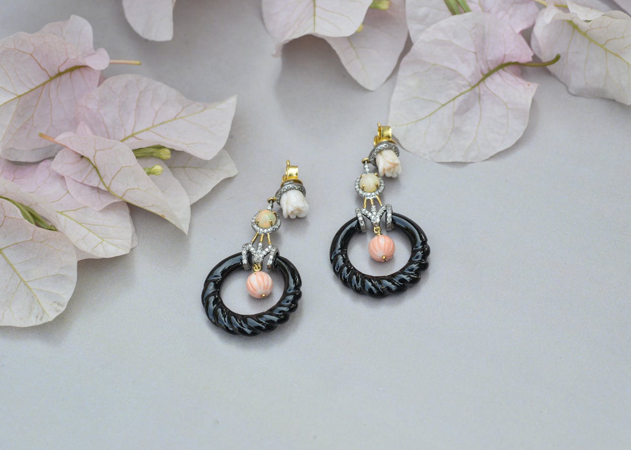 Close-up of handmade floral and gem-adorned dangle earrings with neutral background.