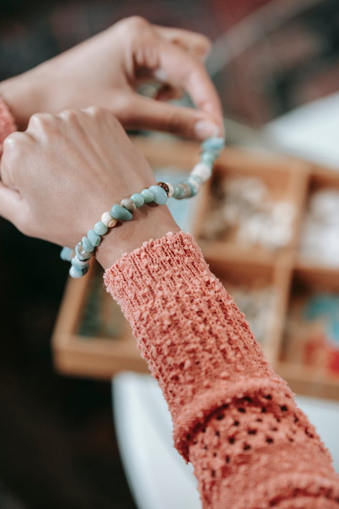 cta-image Close-up of hands wearing a beaded bracelet, showcasing handicraft and lifestyle indoors.